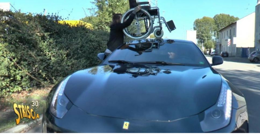 Ferrari sul posto disabili, Striscia la notizia provoca: sedia a rotelle sul tetto della fuoriserie